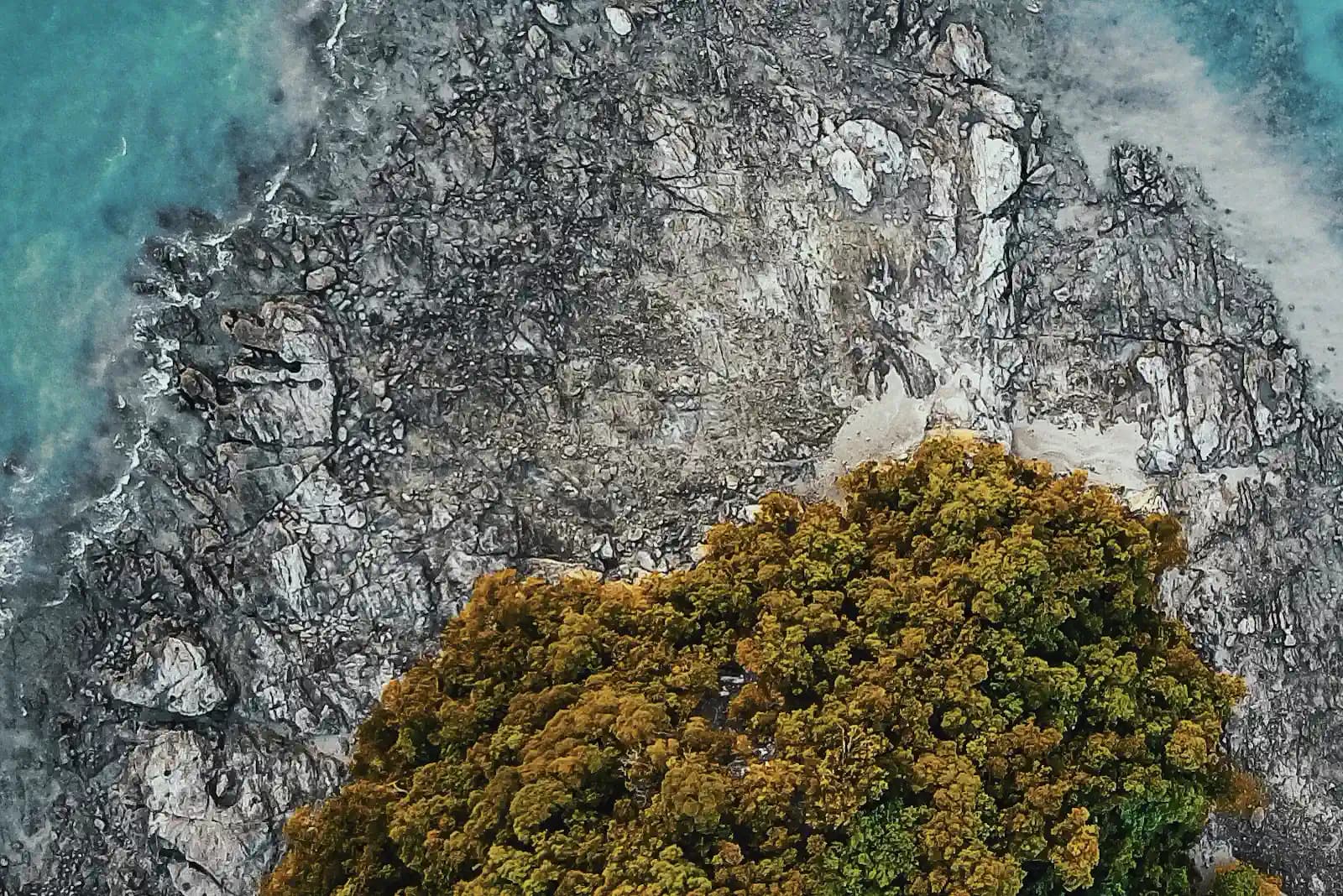 Aerial view of a rocky, forested Langkawi island fringed by turquoise water