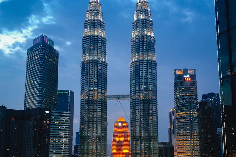 The Petronas Towers lit up at dusk over the Kuala Lumpur skyline