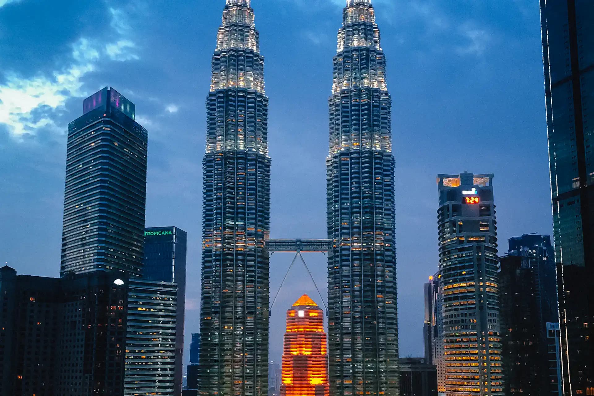 The Petronas Towers lit up at dusk over the Kuala Lumpur skyline